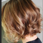 A person with short, wavy, light brown hair, viewed from the side, against a plain background.